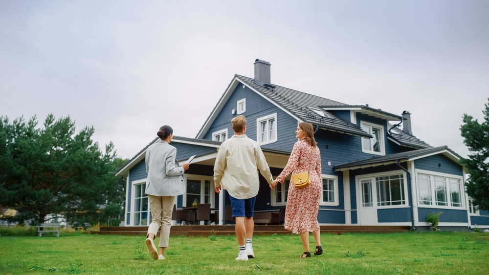 Married couple talking with strata manager outside a house